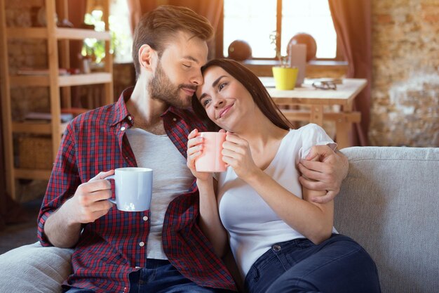Счастливая молодая пара отдыхает в современной домашней гостиной в помещении Влюбленная пара Начало истории любви