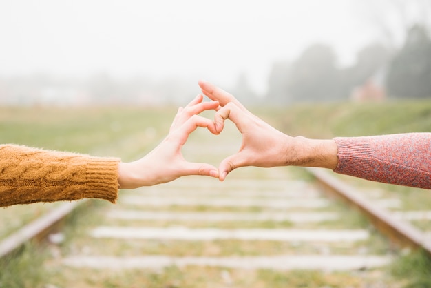 Free photo happy young couple showing heart gesture