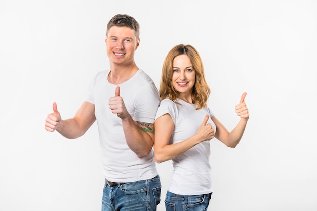 Happy young couple showing thumb up sign against white background