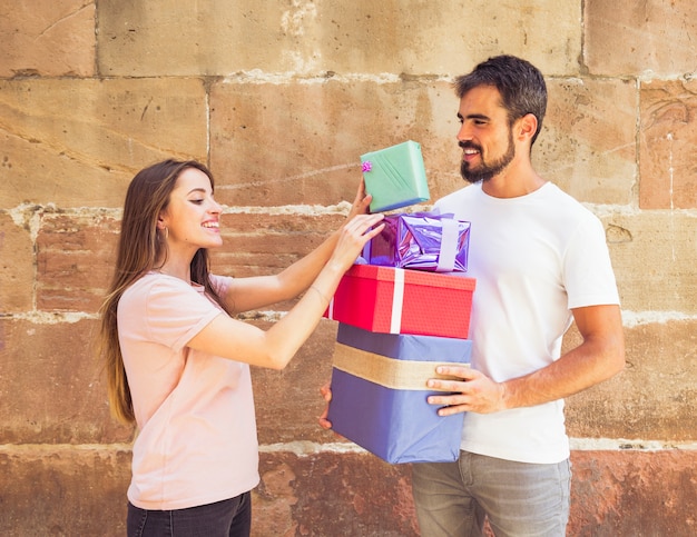 Happy young couple stacking present in front of grunge wall