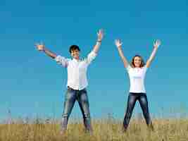 無料写真 手を上げて夏の牧草地に一緒に立っている幸せな若いカップル