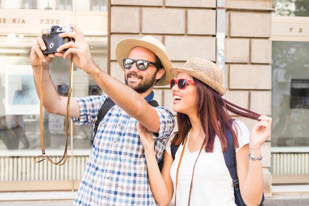 Happy young couple taking selfie on camera in city