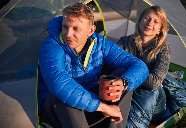 Happy young couple travelers resting in camp tent