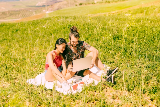 Happy young couple using laptop on rest