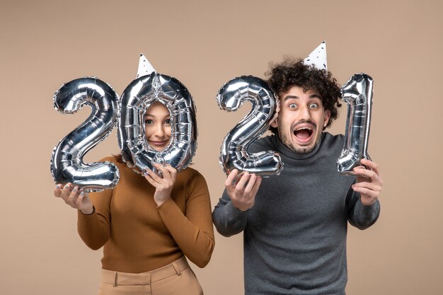 Happy young couple wear new year hat poses for camera Girl showing and and guy with and on gray stock photo