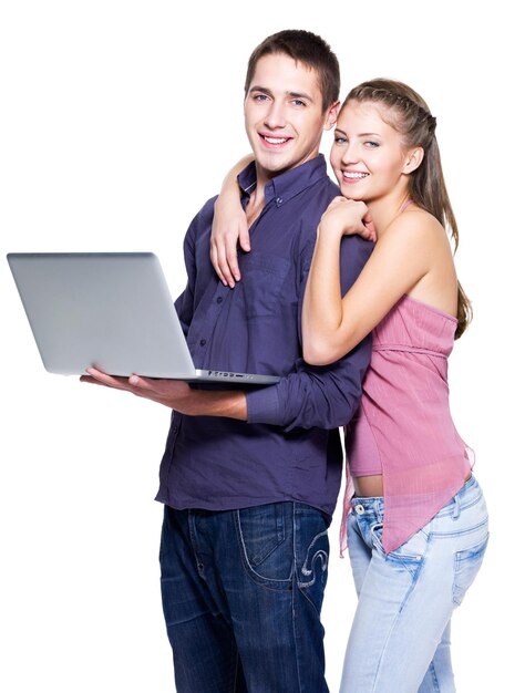 Happy young couple with laptop on white wall