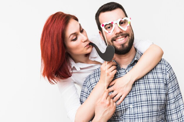 Happy young couple with party props on white background