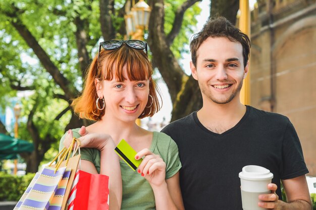 Счастливая молодая пара с хозяйственными сумками после покупок, прогулки по улицам. Понятие консьюмеризма.