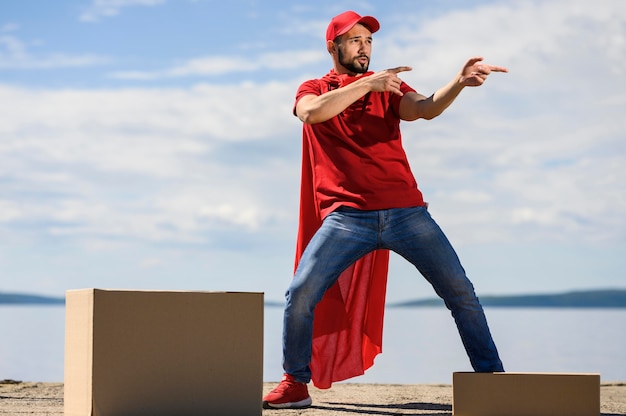 Happy young delivery man wearing superhero cape