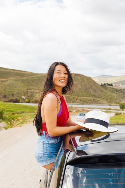 Free photo happy young ethnic female sitting in car in travel