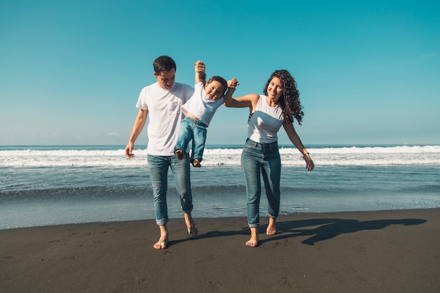 Happy young family having fun with baby on sunny beach