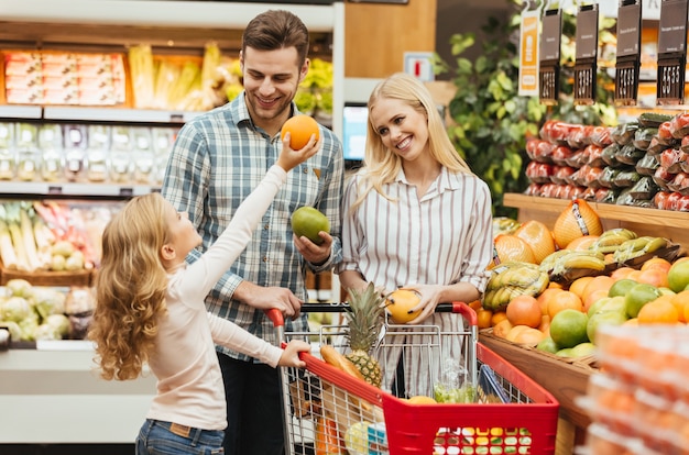 Free photo happy young family standing with a trolley