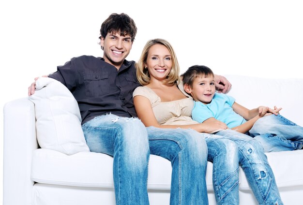 Счастливая молодая семья с ребенком на белом изолированном диване