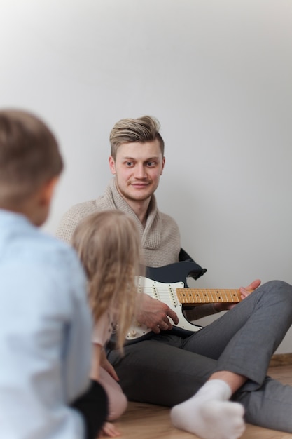 Foto gratuita felice giovane padre con la sua chitarra