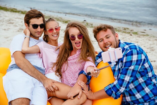 Happy young friends in sunglasses, resting together, taking a selfie on mobile phone