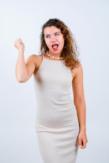 Happy young gilr is looking left by raising up her fist on white background