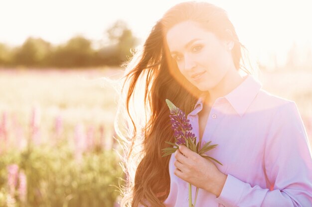 happy young girl holding lupine flower in hands.