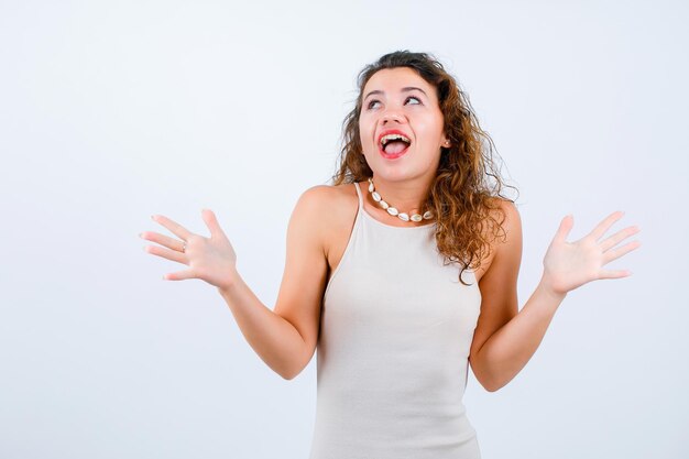 Happy young girl is looking up and opening wide her hands on white background