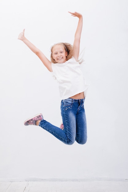 Счастливая молодая девушка прыгает на белом фоне