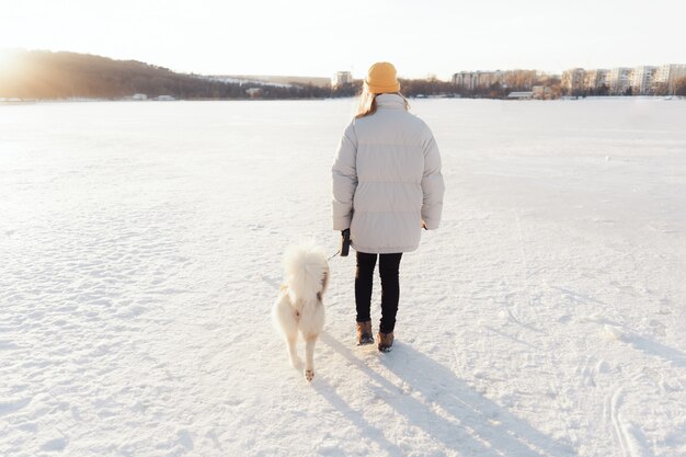 Happy young girl playing with siberian husky dog in winter park