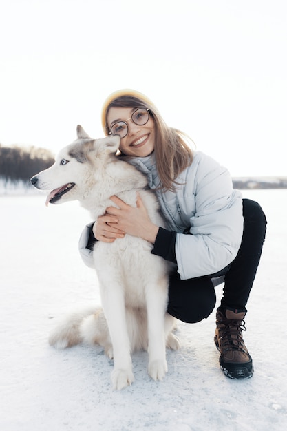 Happy young girl playing with siberian husky dog in winter park