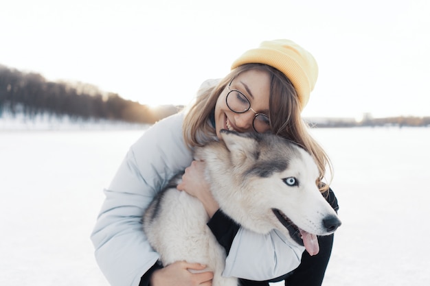 Happy young girl playing with siberian husky dog in winter park