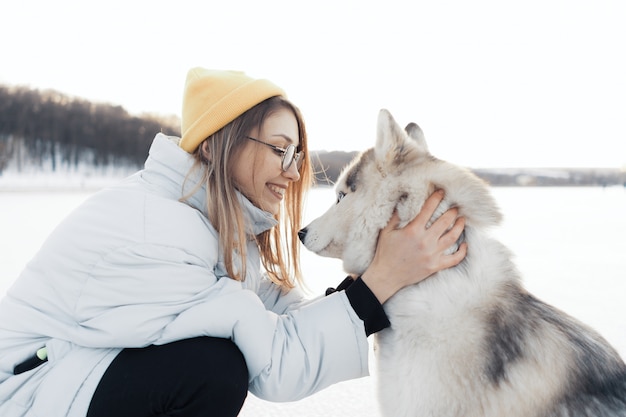 Happy young girl playing with siberian husky dog in winter park