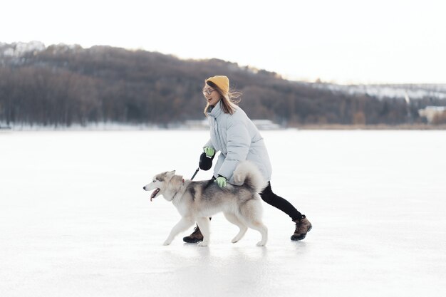 Happy young girl playing with siberian husky dog in winter park