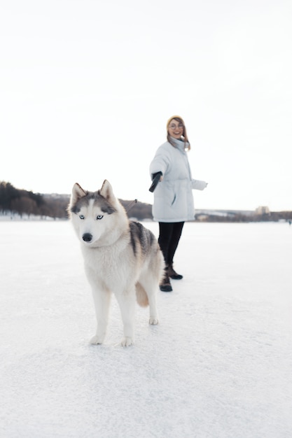 Happy young girl playing with siberian husky dog in winter park