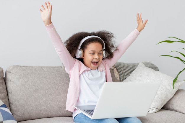 Free photo happy young girl watching cartoons on laptop