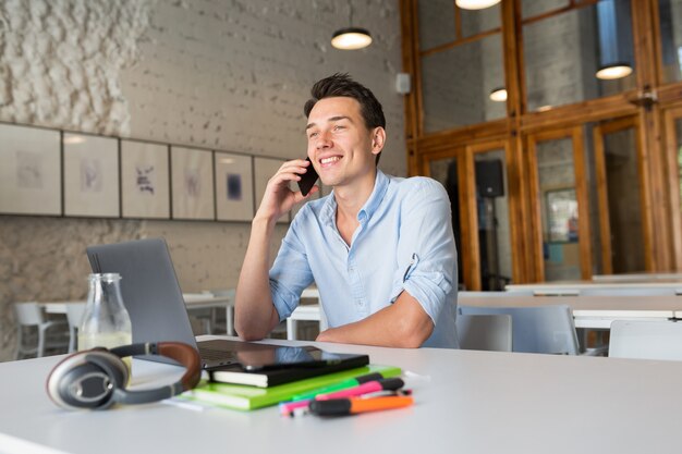 Happy young handsome man sitting in co-working office