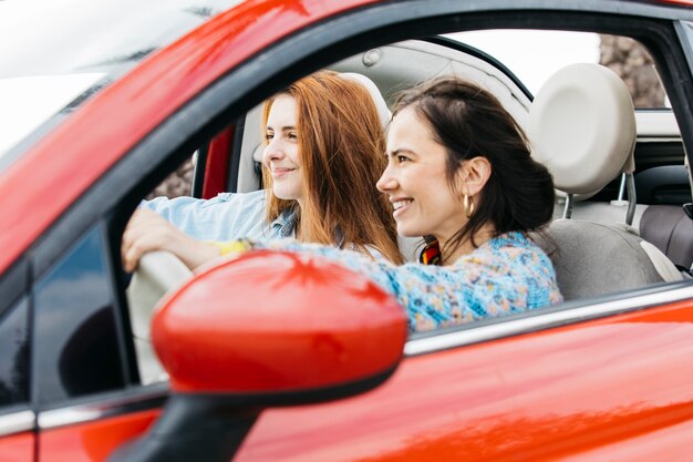 Happy young ladies sitting in car