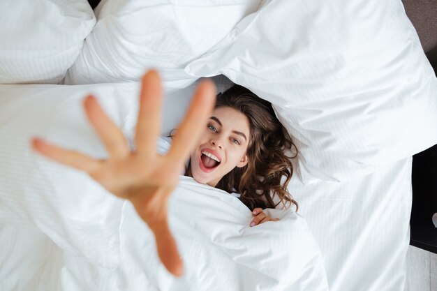 잠옷을 입고 행복 한 젊은 여자는 침대에 놓여