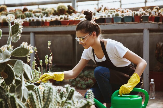 Happy young lady in glasses standing in greenhouse