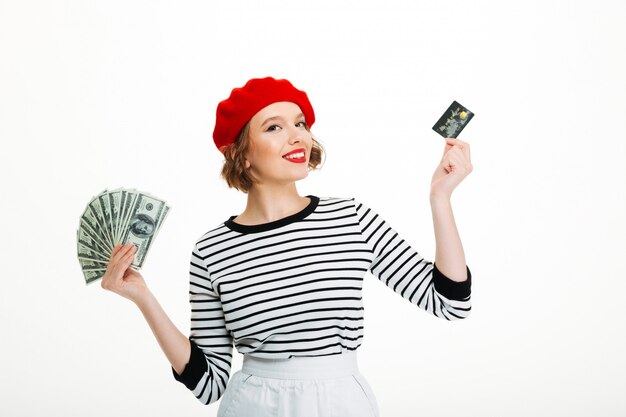 お金のドルとクレジットカードを保持している幸せな若い女性