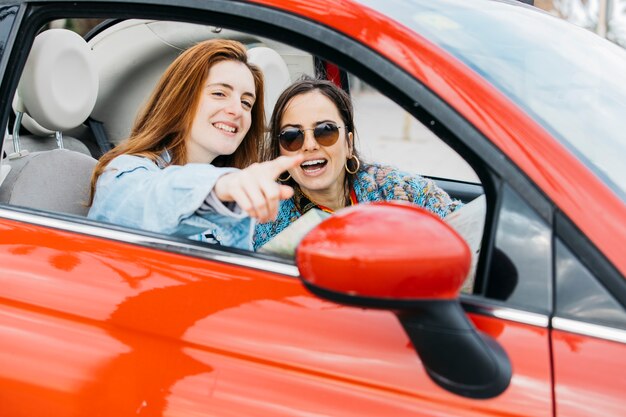 陽気な女性を指していると車の中で座っている幸せな若い女性