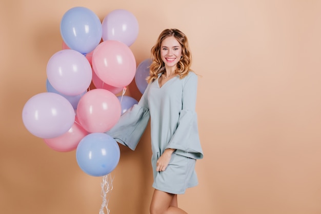 Счастливая молодая леди в модном синем платье позирует с воздушными шарами