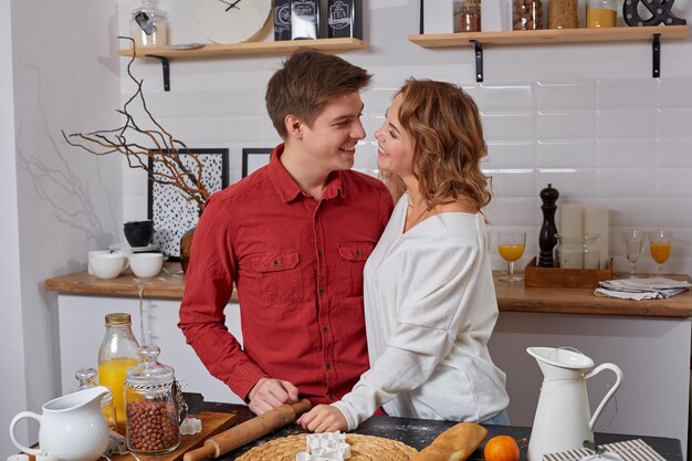 Happy young lovely couple on kitchen hugging each other. They enjoy spending time togehter. They show emotions to each other