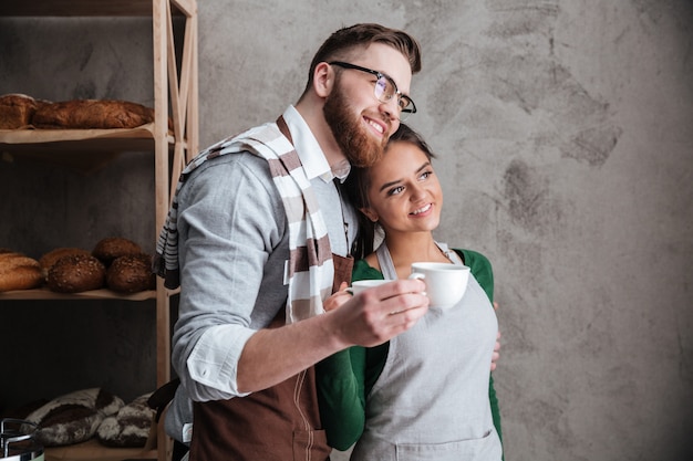 Happy young loving couple bakers drinking coffee.