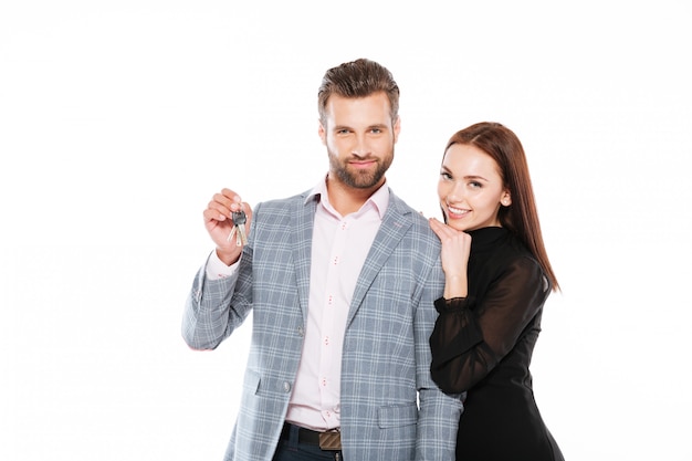 Happy young loving couple holding keys.