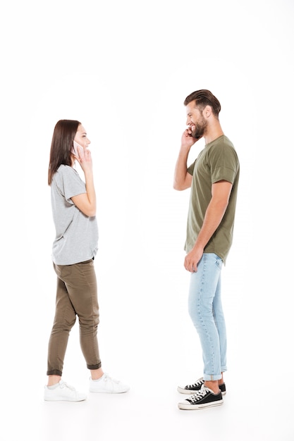 Happy young loving couple talking by phones.