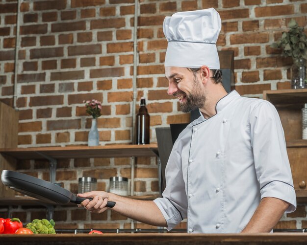幸せな若い男性のシェフ、料理を準備する、キッチン