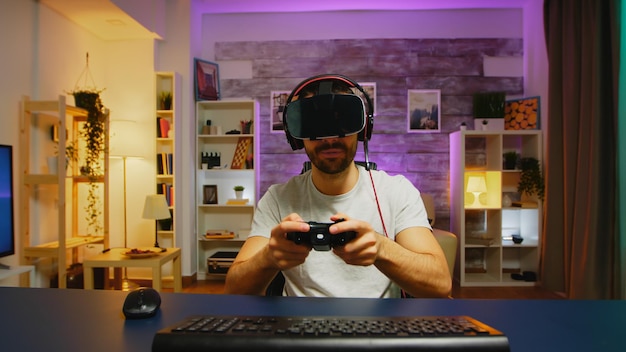 Счастливый молодой человек после его победы во время игры в видеоигры в гарнитуре виртуальной реальности.