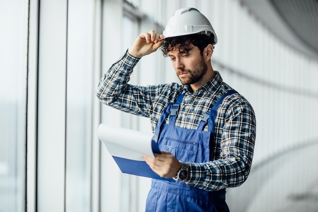 無料写真 フォルダーを保持しているヘルメットの幸せな若い男の建築家