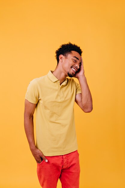 Happy young man in bright clothes enjoying. Blithesome male model with short black hair standing.