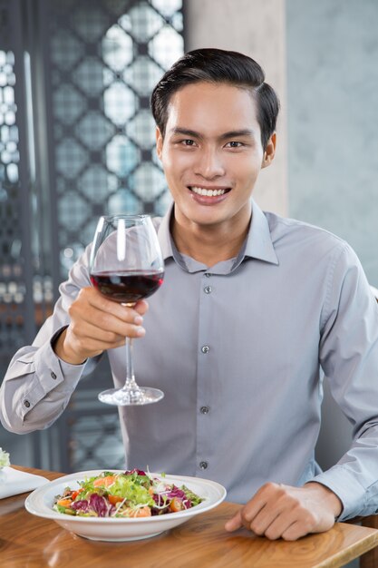 Happy Young Man Drinking Red Wine in Restaurant