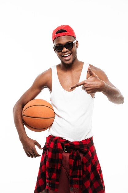 Счастливый молодой человек, держащий баскетбольный мяч и указывая прочь