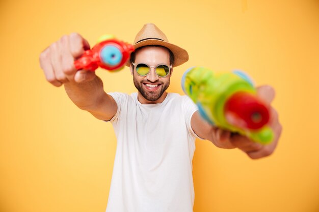 Happy young man holding toy water guns.