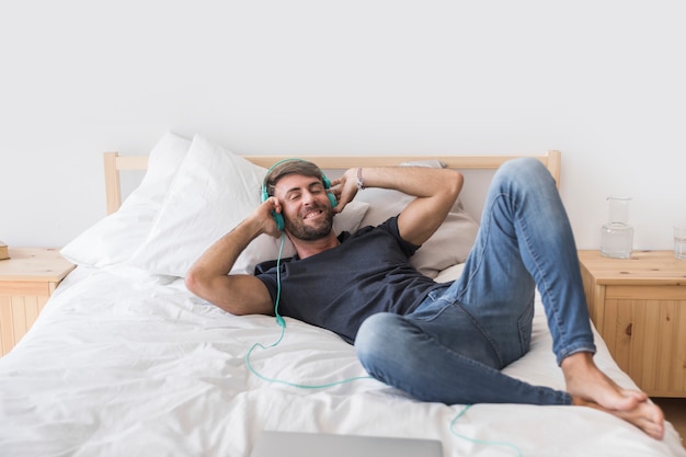 침대에서 행복 한 젊은 사람이 듣는 음악