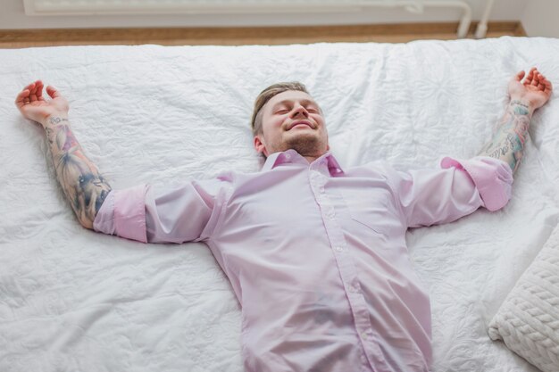 Happy young man lying on the bed